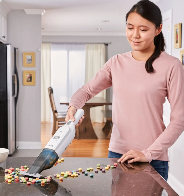 woman in pink shirt using dustbuster on counter with candy spill