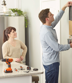 Man hanging a picture in a kitchen