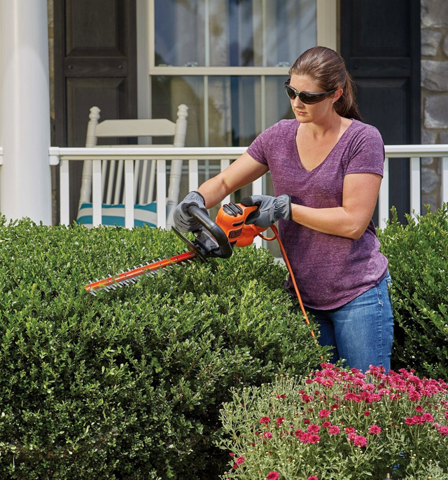 Woman using BLACK+DECKER hedge trimmer outside