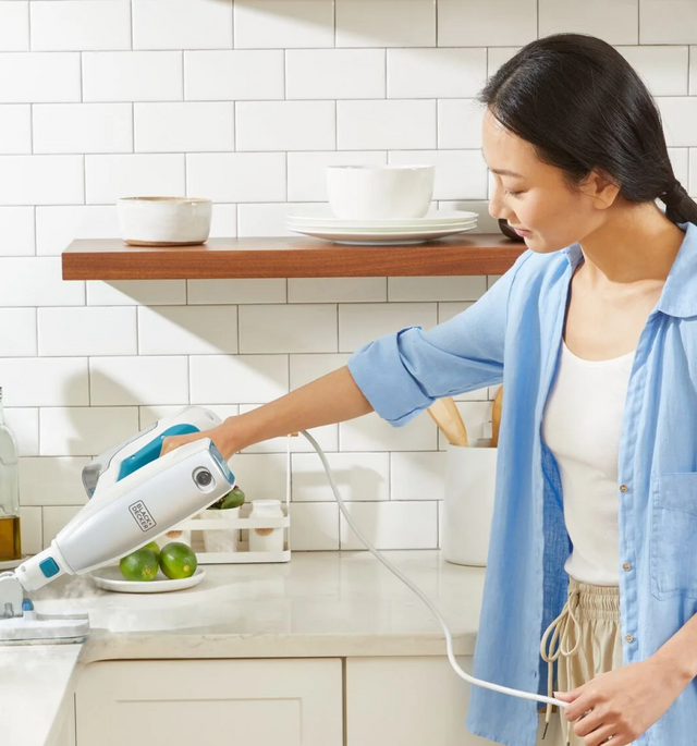 Woman using a steam mop counter attachment on a kitchen counter